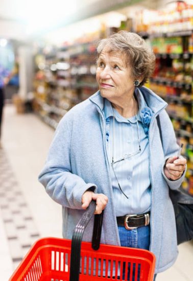 Looking a little lost, a senior woman looks at products on the shelves of a supermarket.